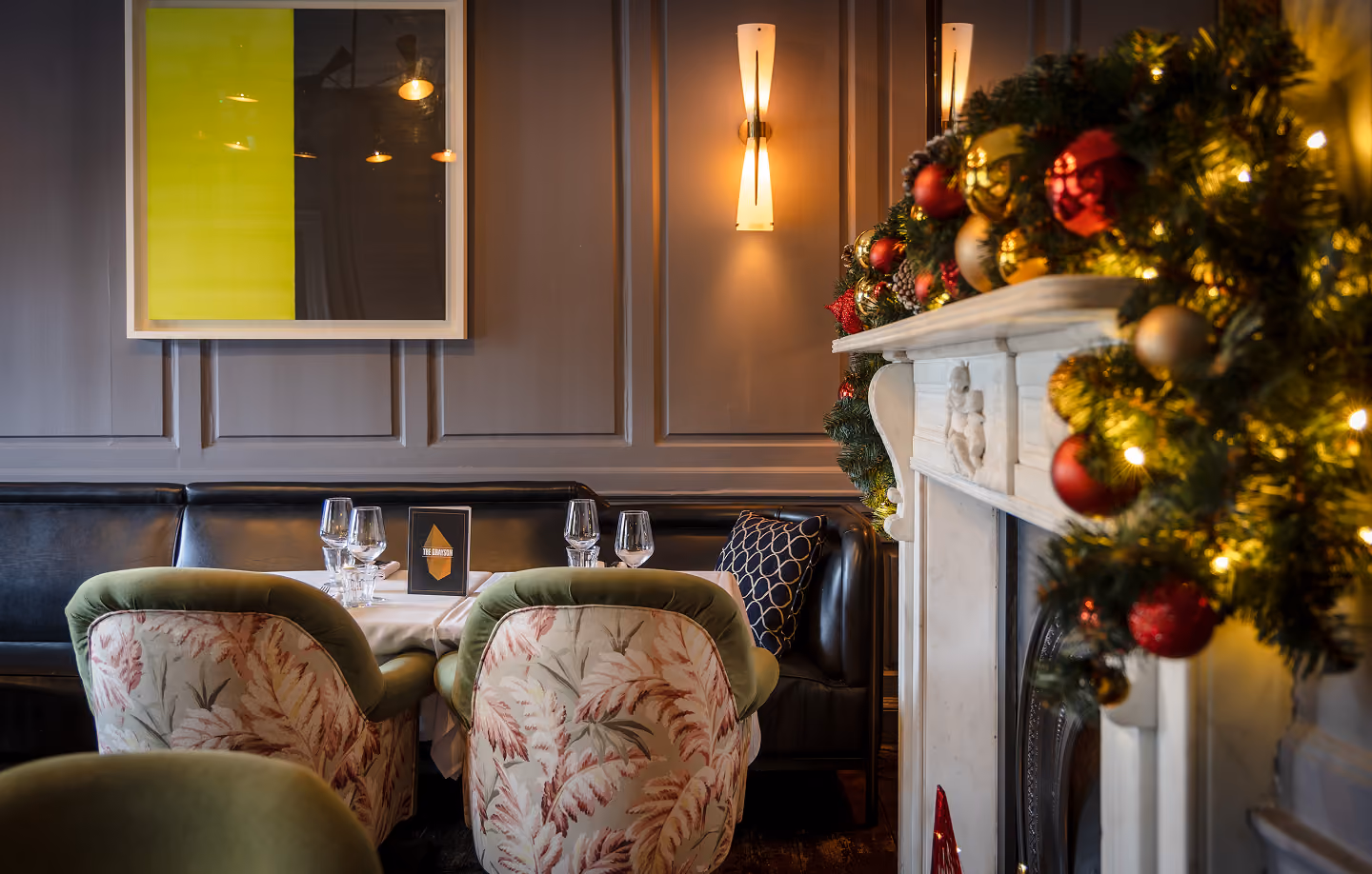 Armchairs beside the garlanded fireplace at The Grayson
