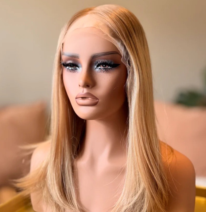 Mannequin head with long blonde hair and dramatic makeup, including blue eyeshadow and thick eyeliner.