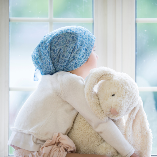 Child in a blue headscarf hugging a large plush bunny near a window.