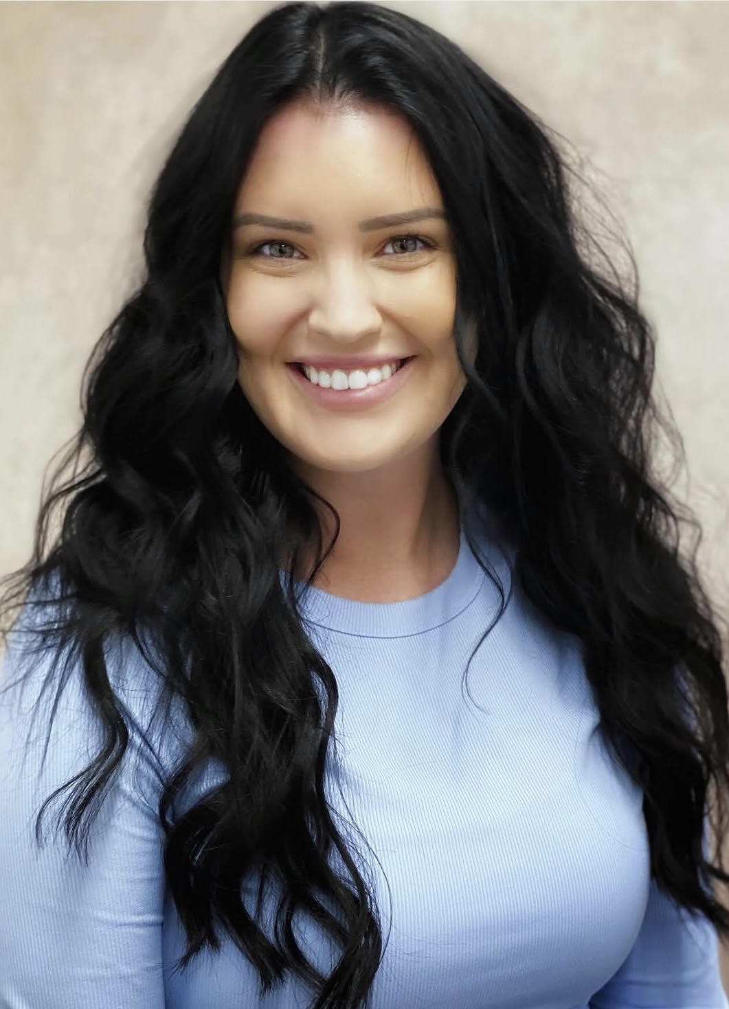 Shiny wavy light brown hair styled with soft curls viewed from the back.