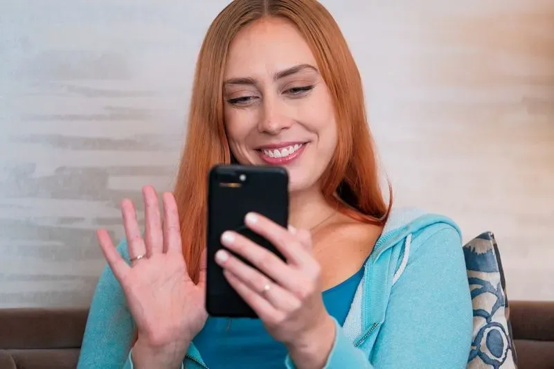 Female waiving to psychiatrist on a cell phone- online meeting