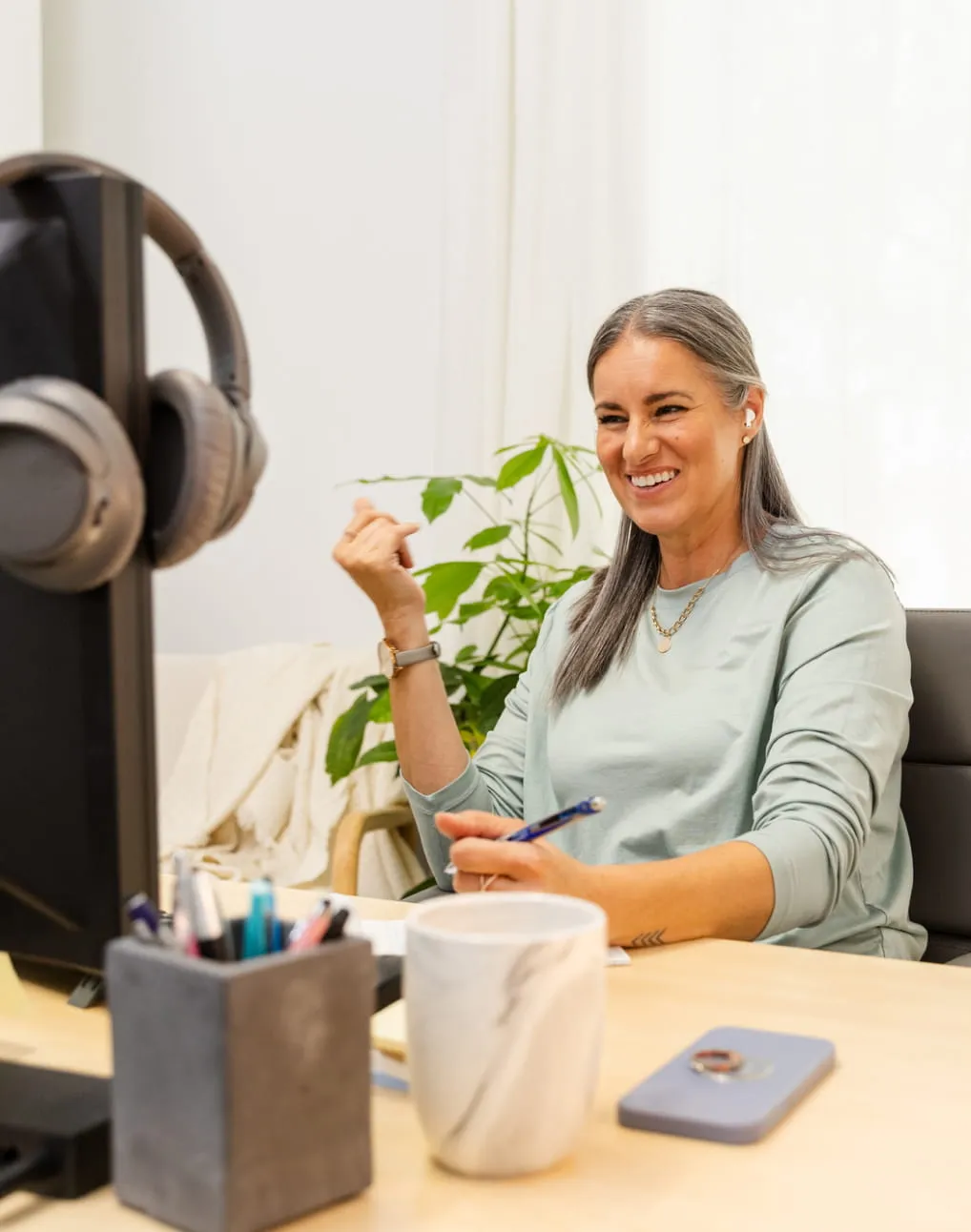 Woman smiling during a virtual appointment at her desk using a computer and headphones