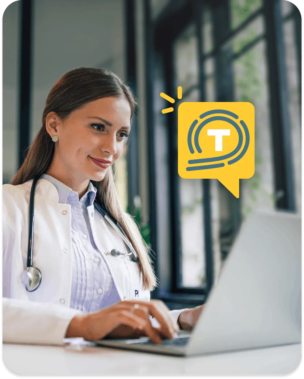 Female doctor in white coat with stethoscope using a laptop in a bright office.
