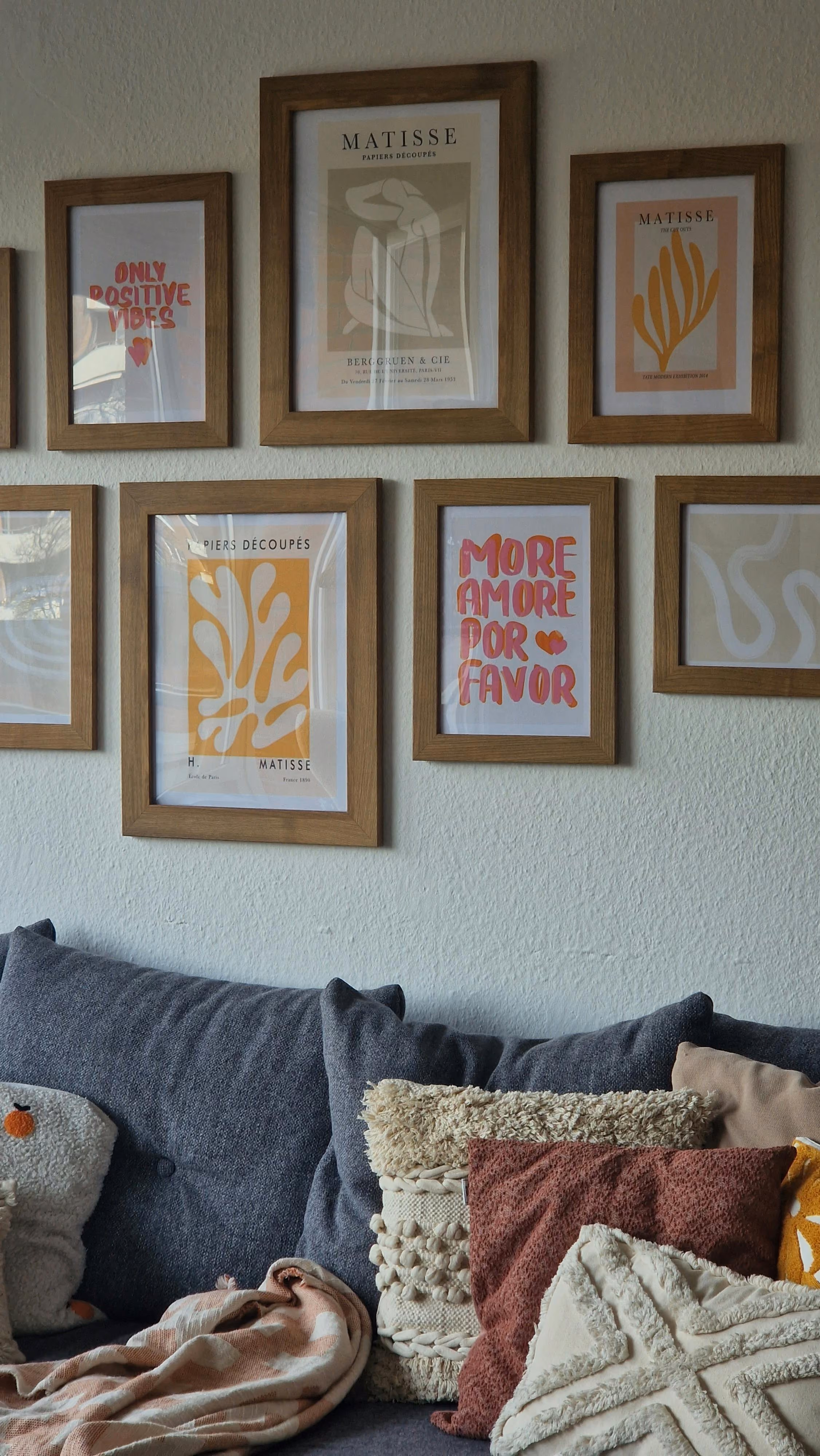 Gallery wall of framed prints above a sofa with cushions
