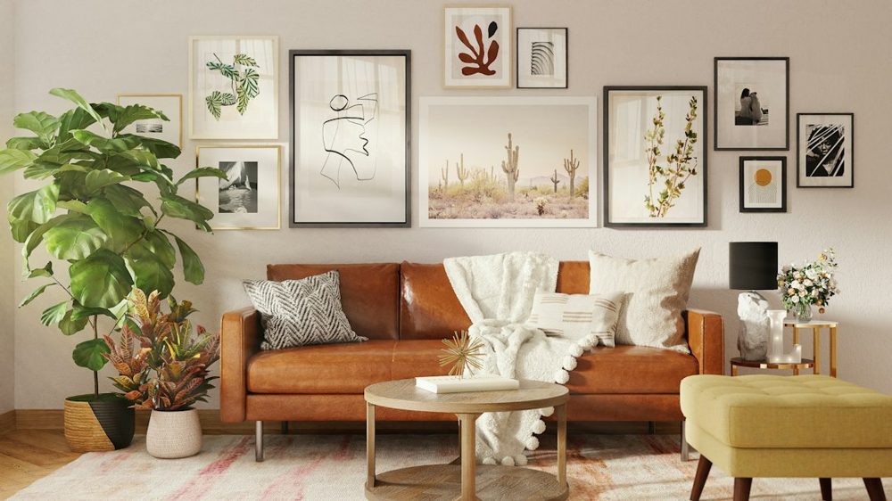 A brown leather sofa with a white throw blanket and gallery wall behind