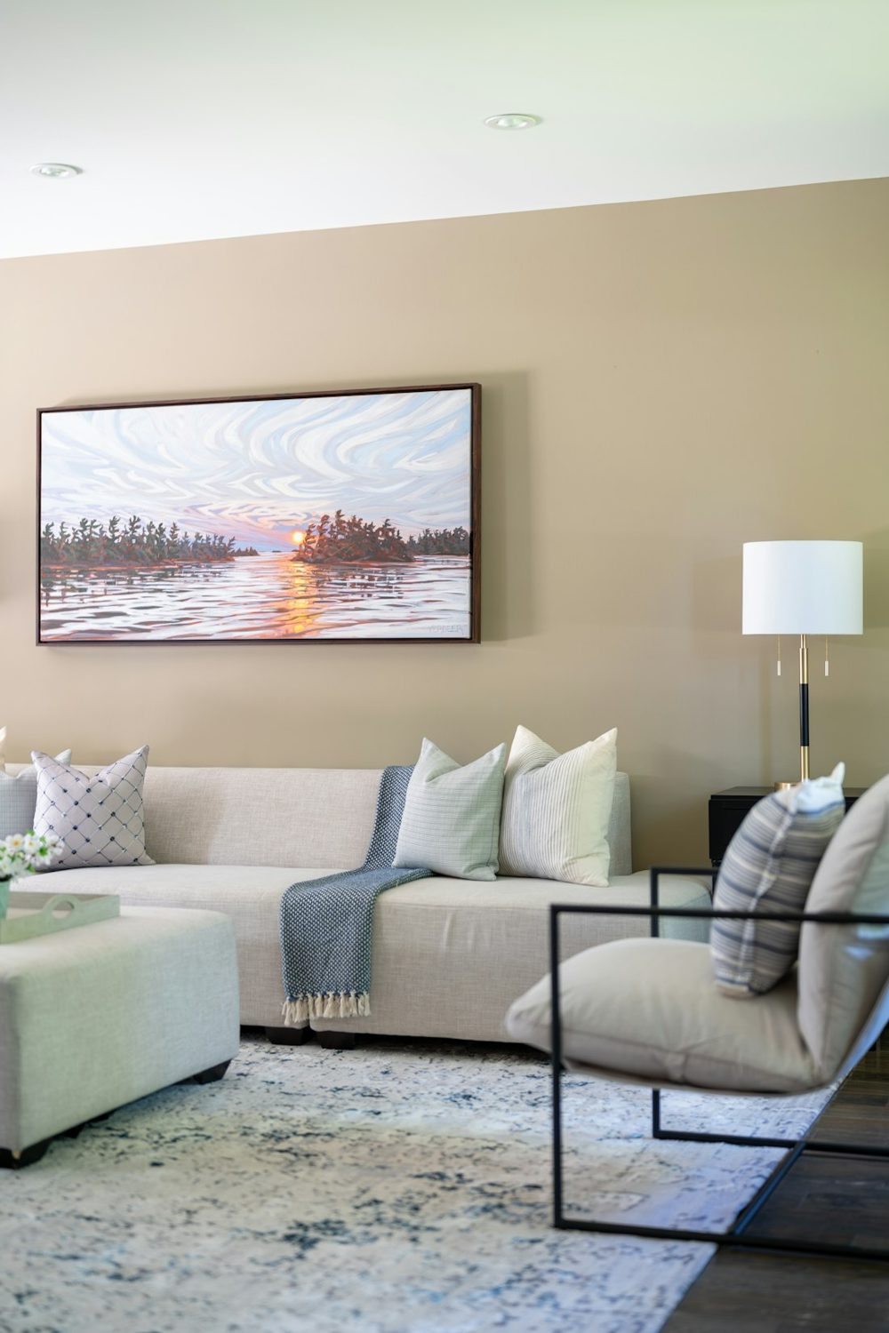 Elegant living room with a sofa, armchair, and sunset painting