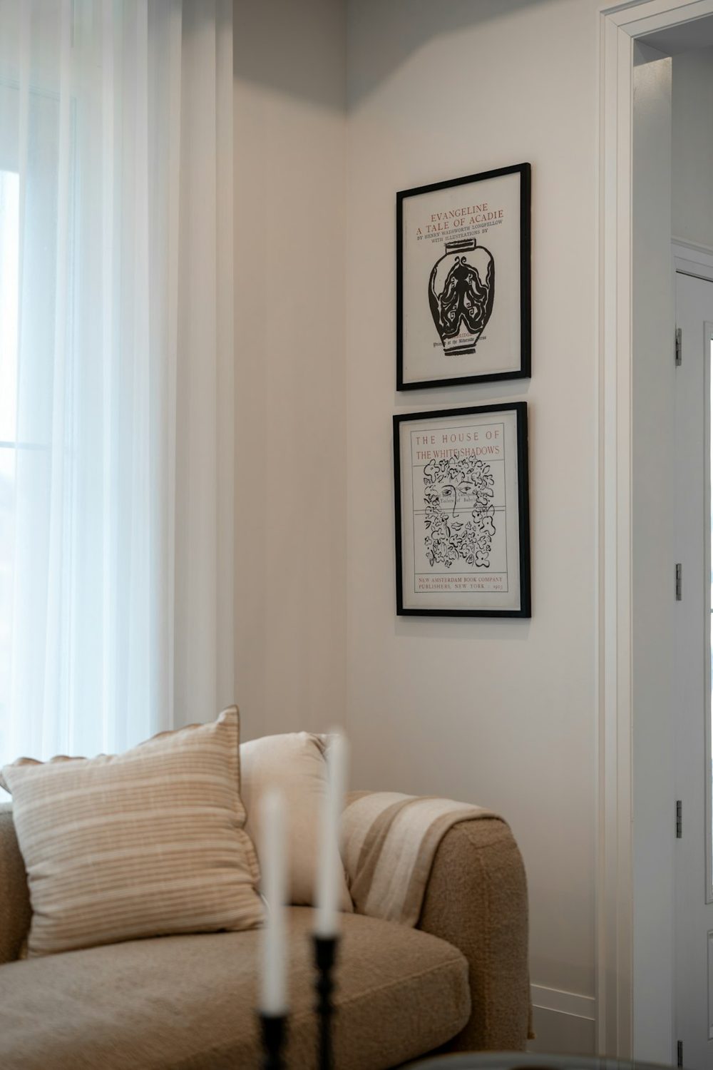 Two framed artworks hang on a wall above a sofa