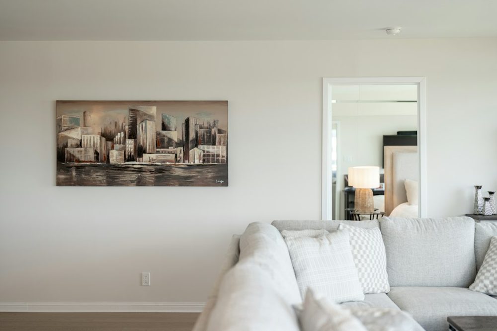 Contemporary living room featuring cityscape artwork and a light sofa