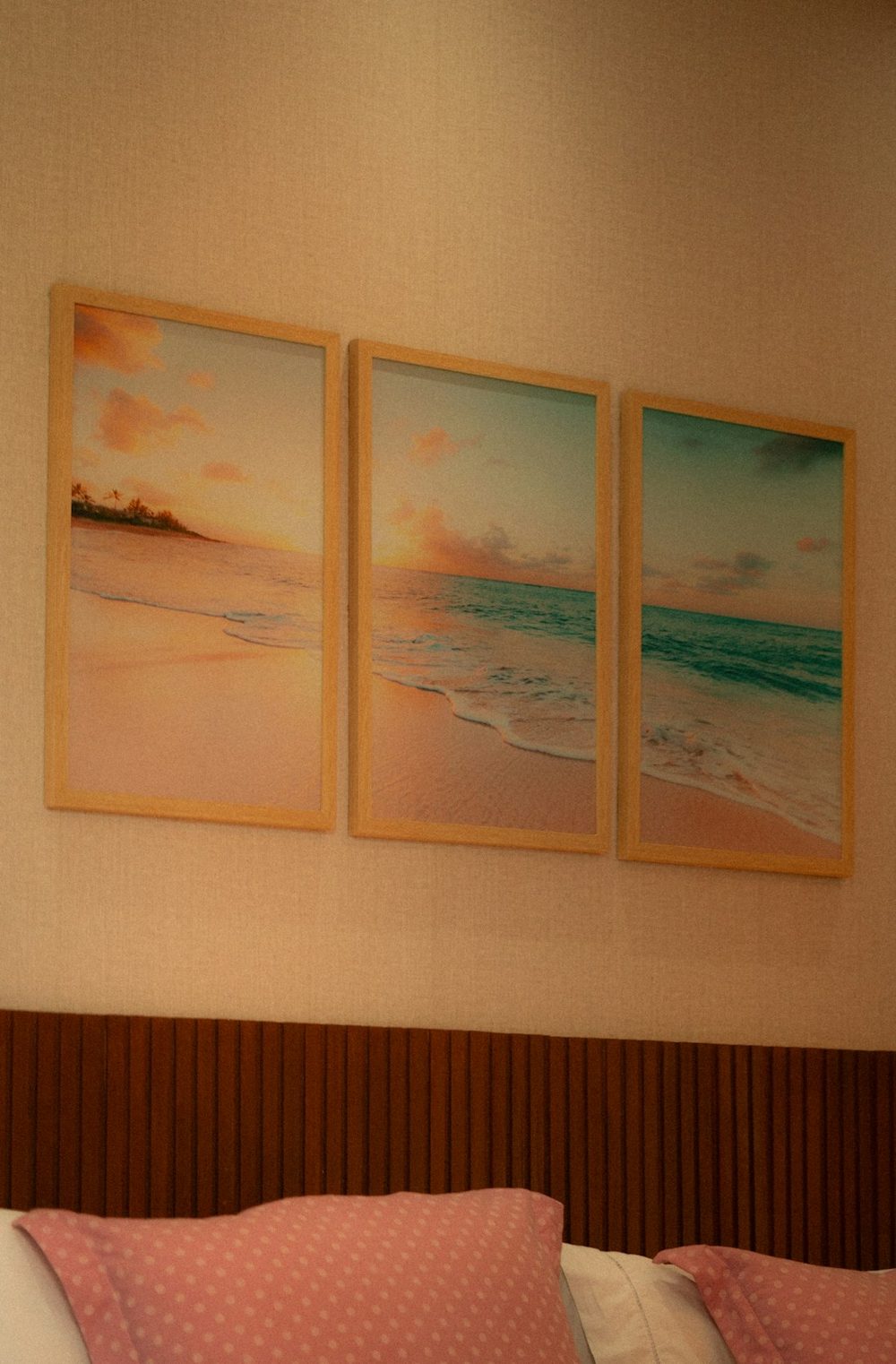 Three framed beach sunset artworks above a headboard