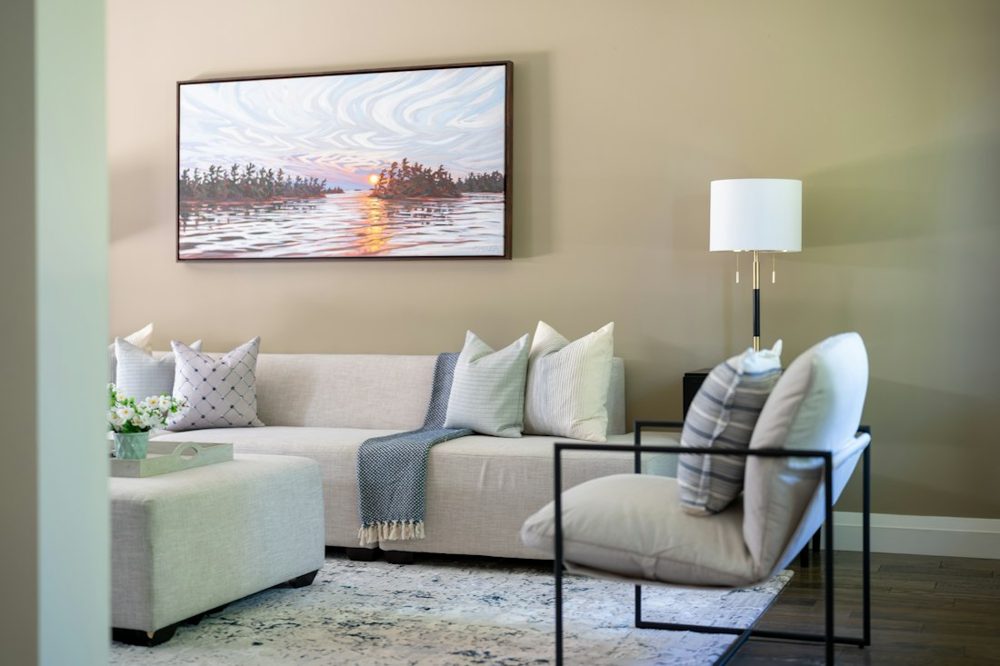 Living room with light sofa, armchair, lamp, and sunset painting