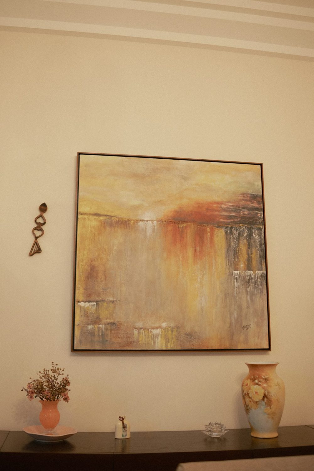 Abstract painting with warm colors above a vase