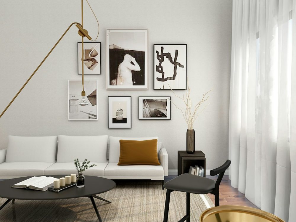 A white sofa with a mustard pillow in a living room with framed art