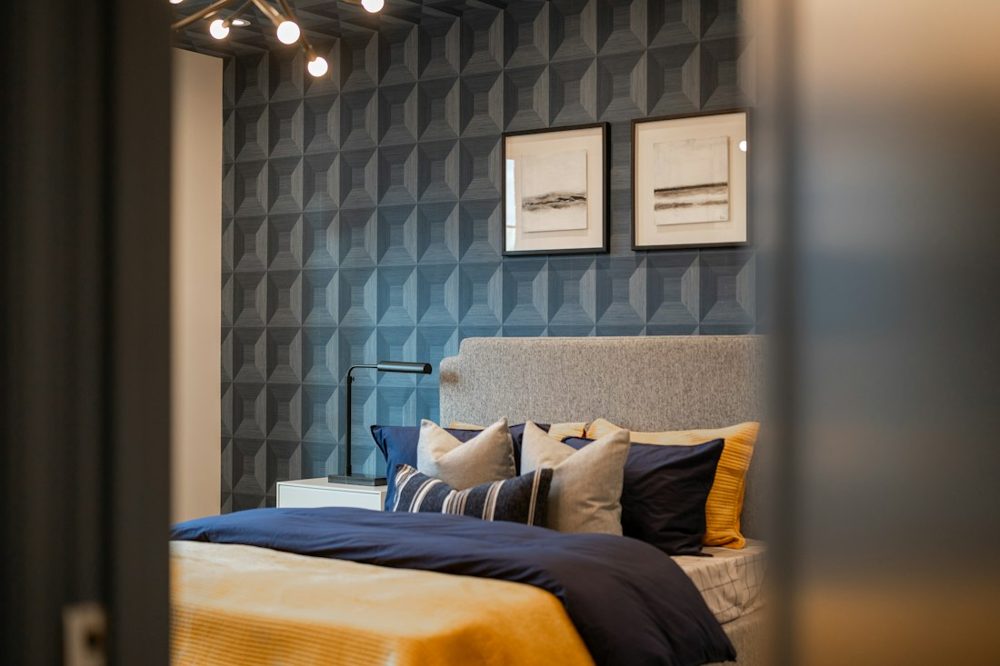 A modern bedroom with a textured blue wall and artwork