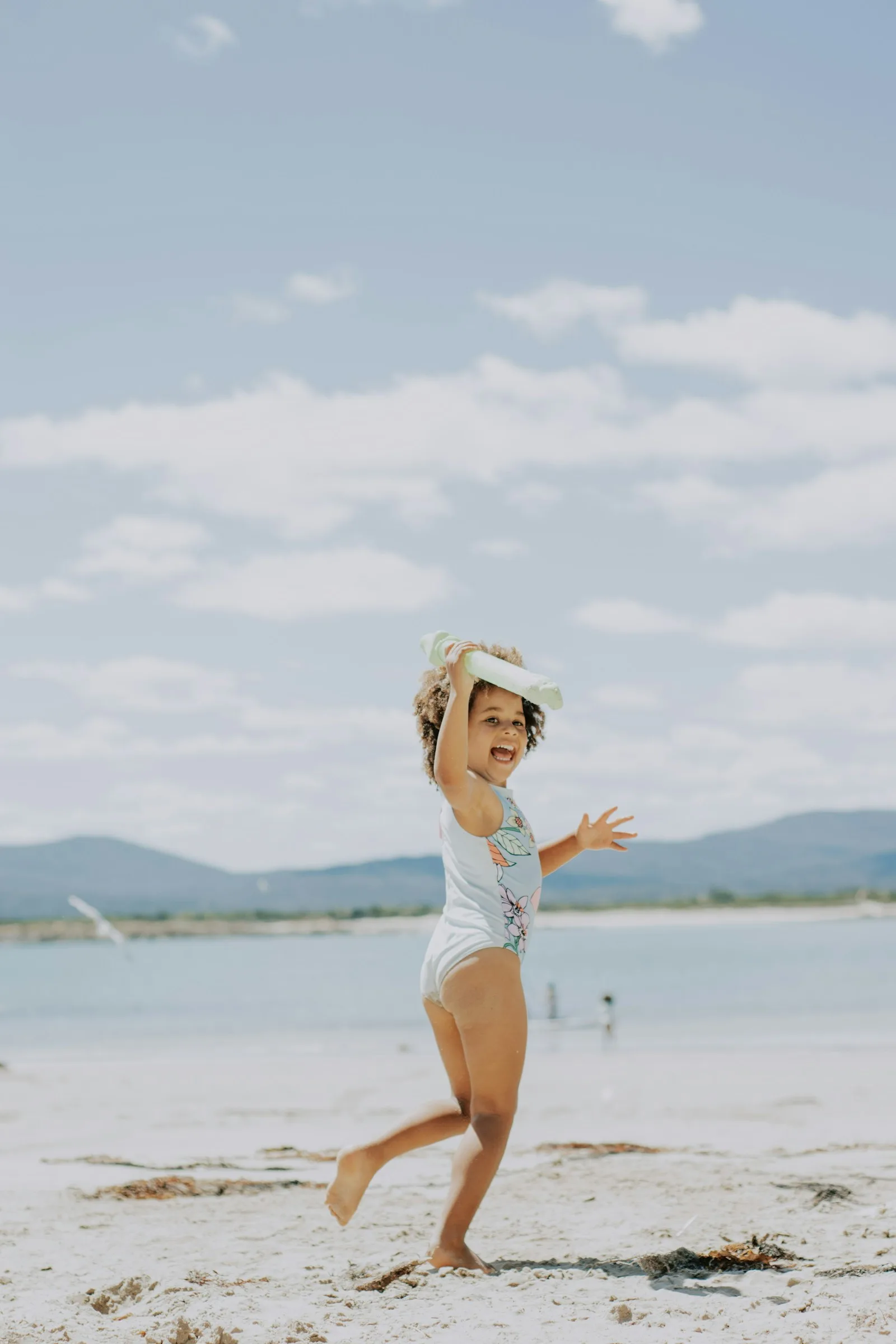 Little girl in a sun hat running on the beach