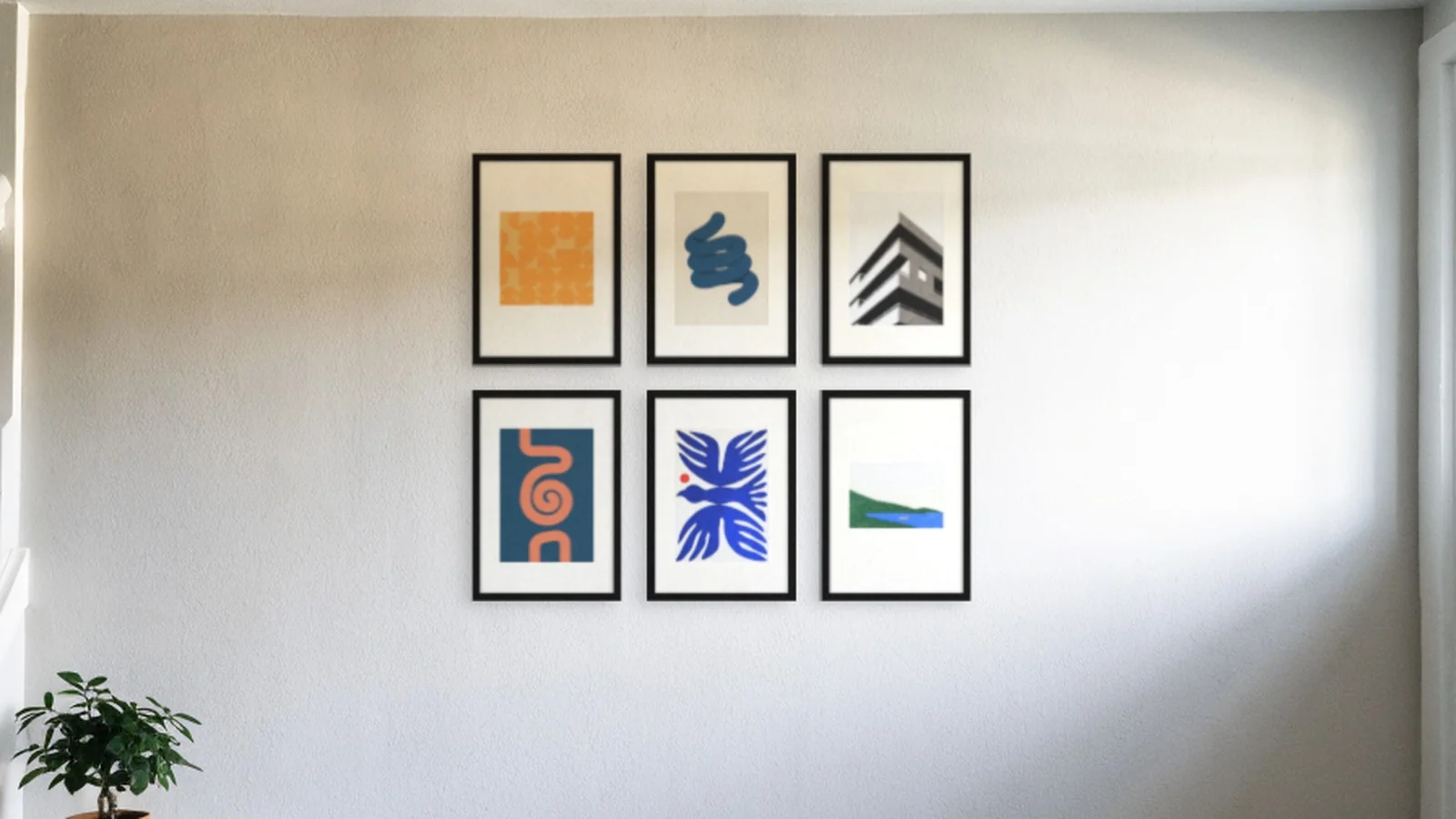 Six prints in black frames hung in a two by three grid on a hallway wall
