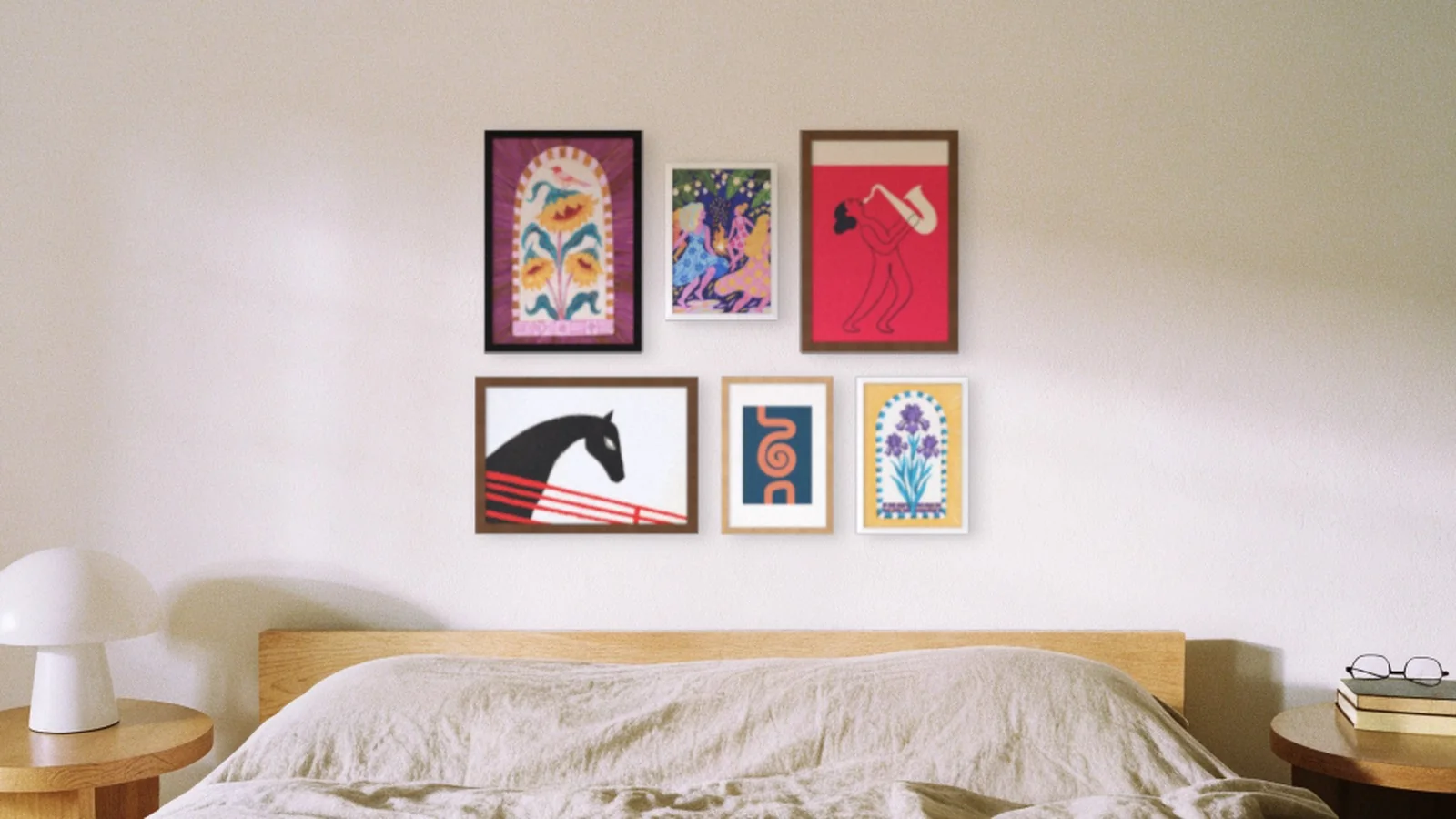 An eclectic gallery wall of six prints in mixed frames and sizes above a bed