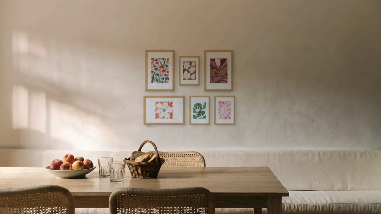 Six botanical prints in oak frames in a salon arrangement above a bench in a kitchen diner