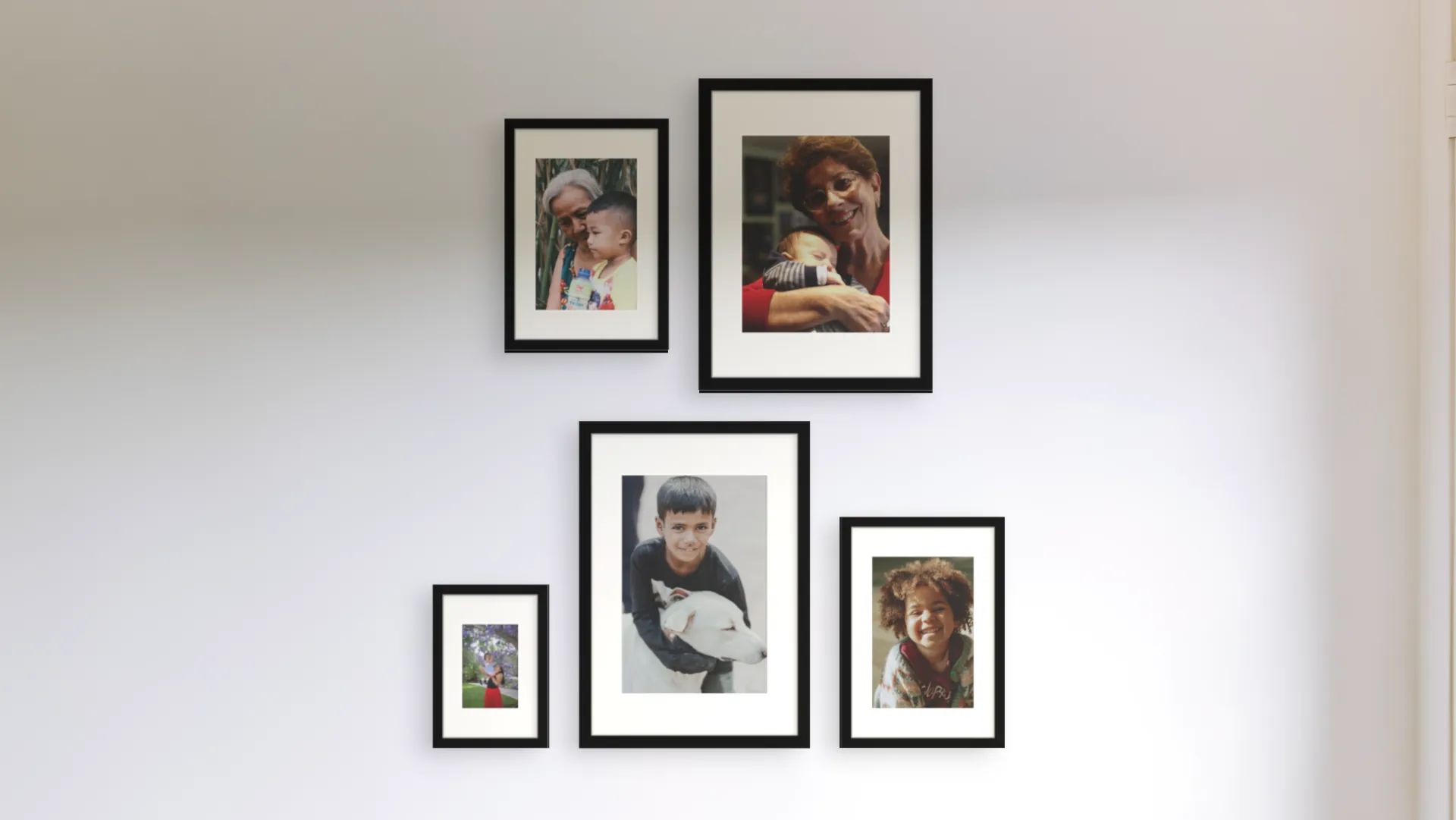 Five family photos in black frames in a cluster on a hallway wall