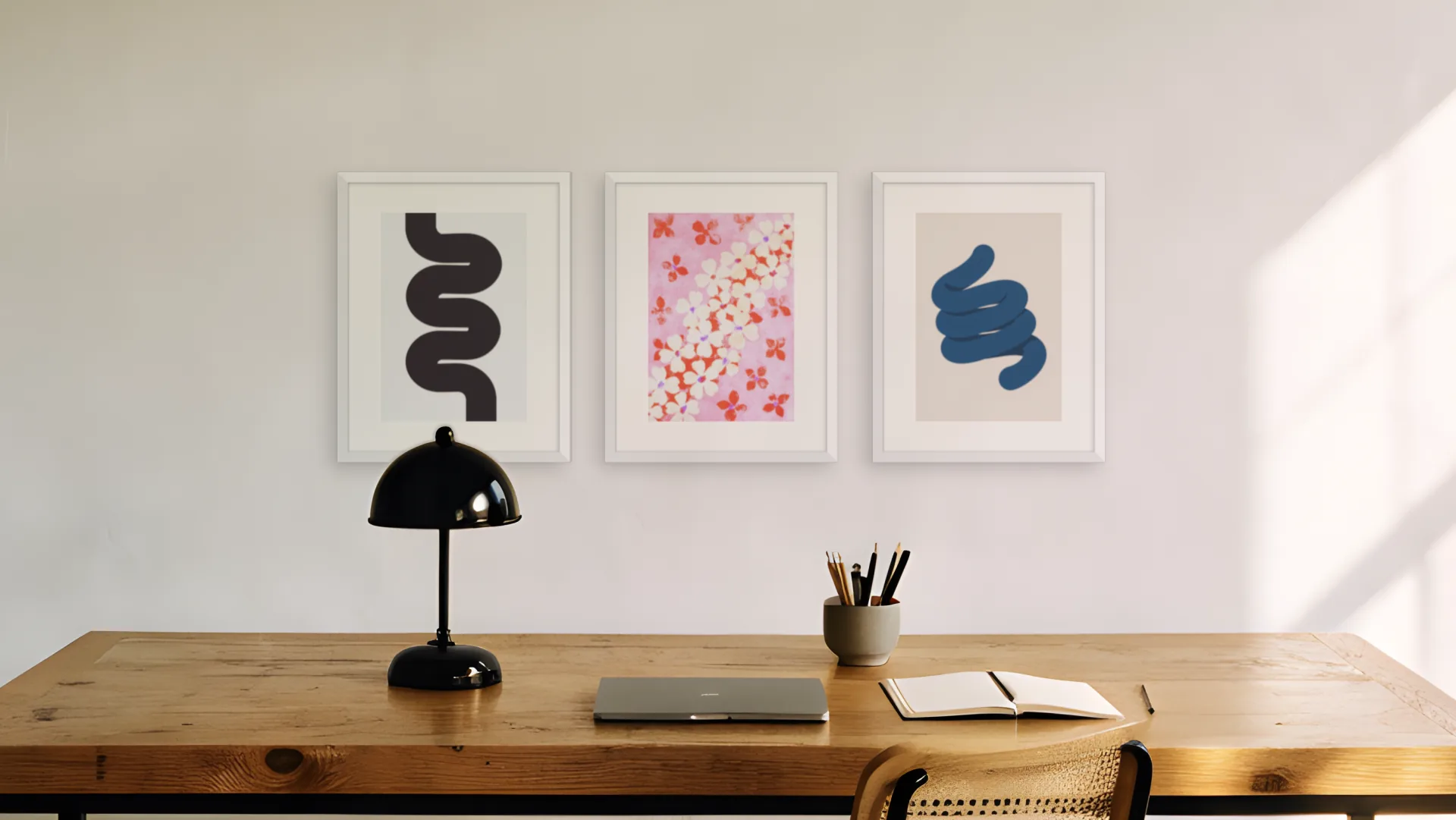 Minimal gallery wall idea: three prints in white frames in a triptych layout above a desk in a home office