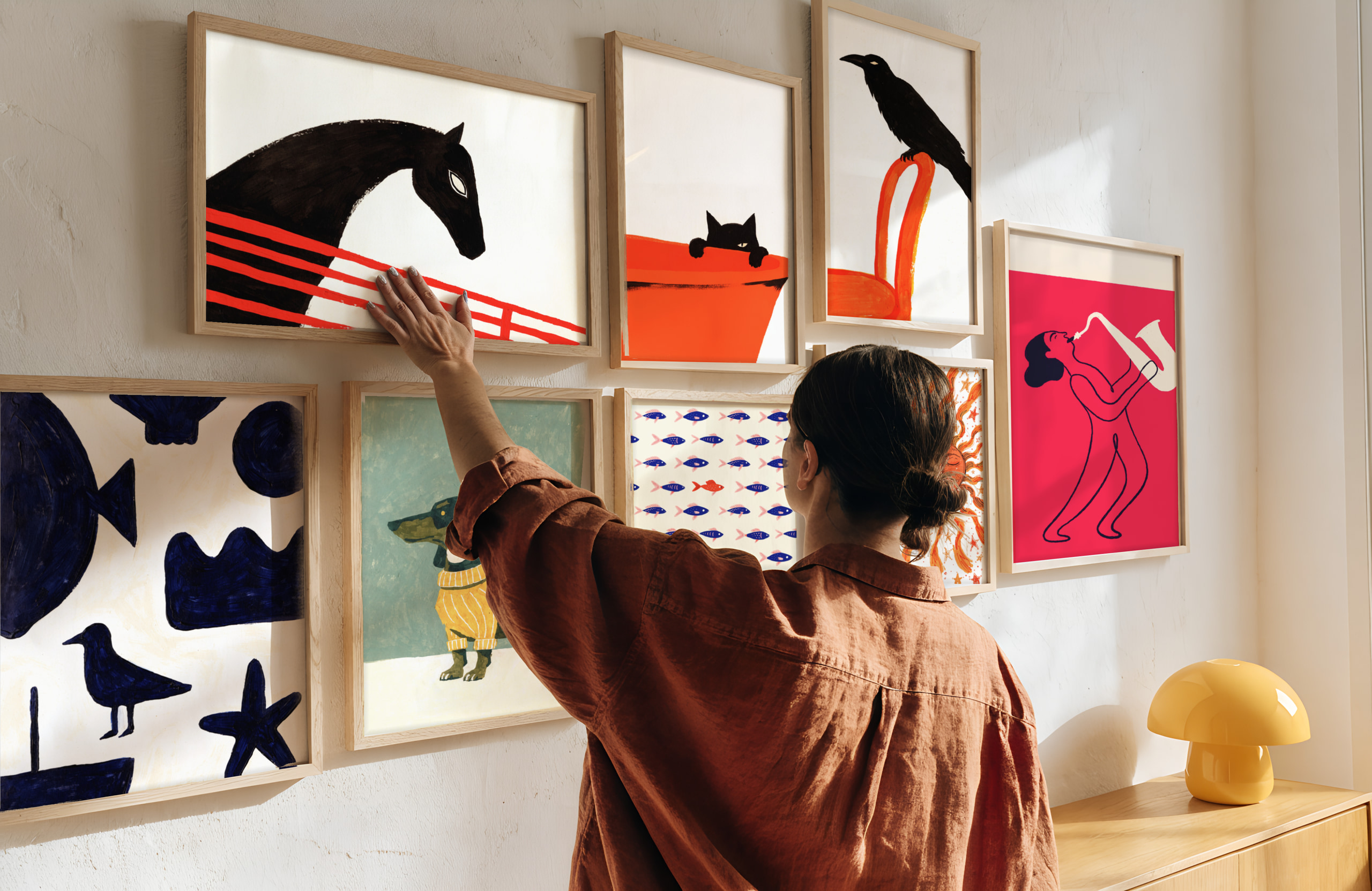 Woman hanging a framed print on a gallery wall with a horse print
