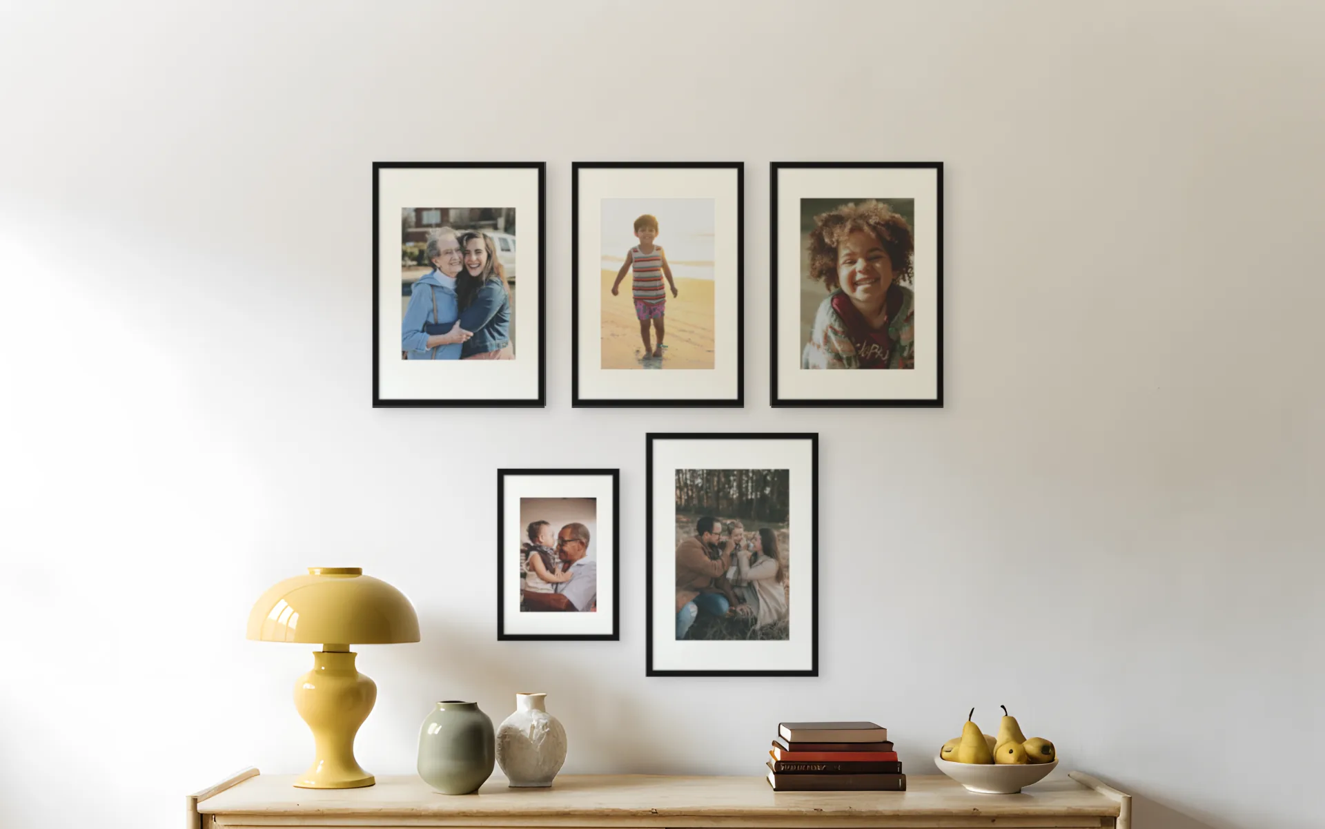 Five family photos in mixed frame sizes, one black frame finish, above a sideboard in a living room