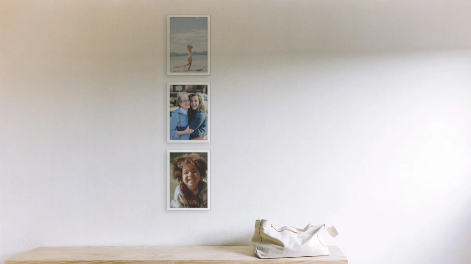 Hallway gallery wall idea: three family photos in a column layout above a bench in a hallway.