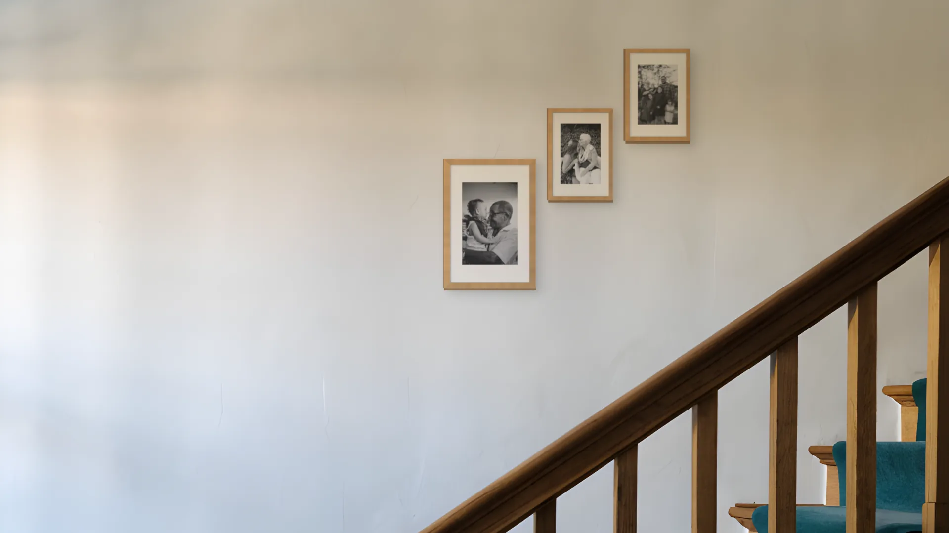 Staircase gallery wall idea: three black and white family photos in oak frames climbing a staircase wall.