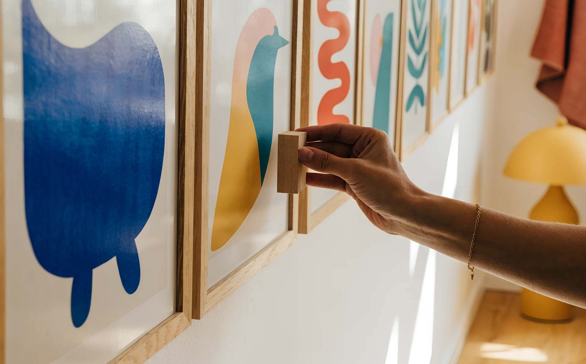 A hand holds a wooden spacer between two frames to check an even gap