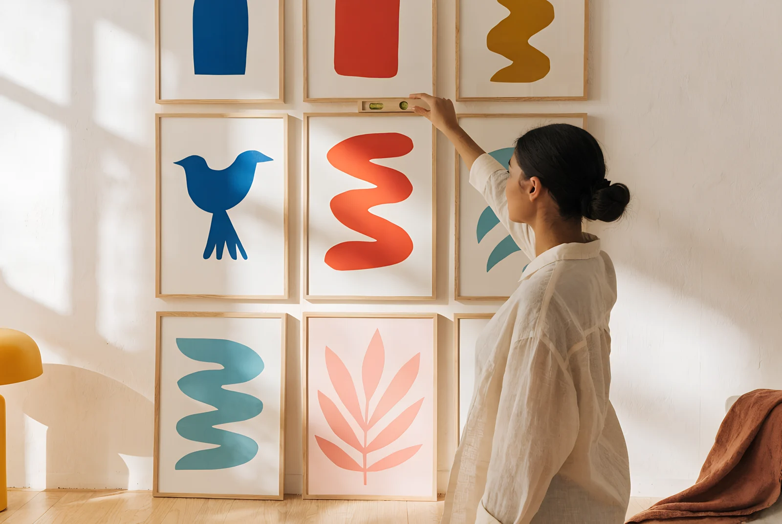 A woman checks a frame is level with a small spirit level on a grid gallery wall