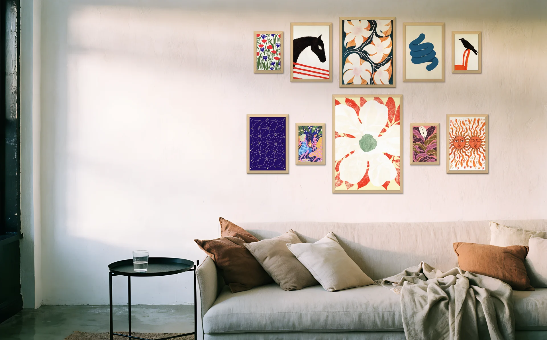 A grand salon gallery wall of ten frames above a linen sofa
