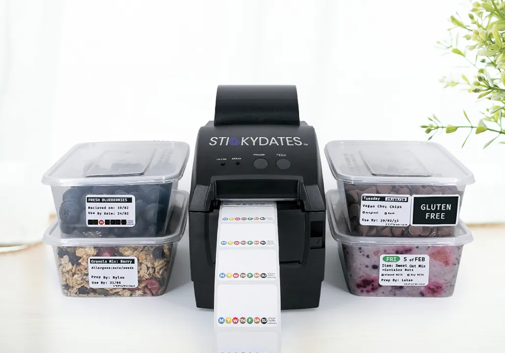 StickyDates label printer with plastic containers of blueberries, granola, chocolate chips, and oat mix.