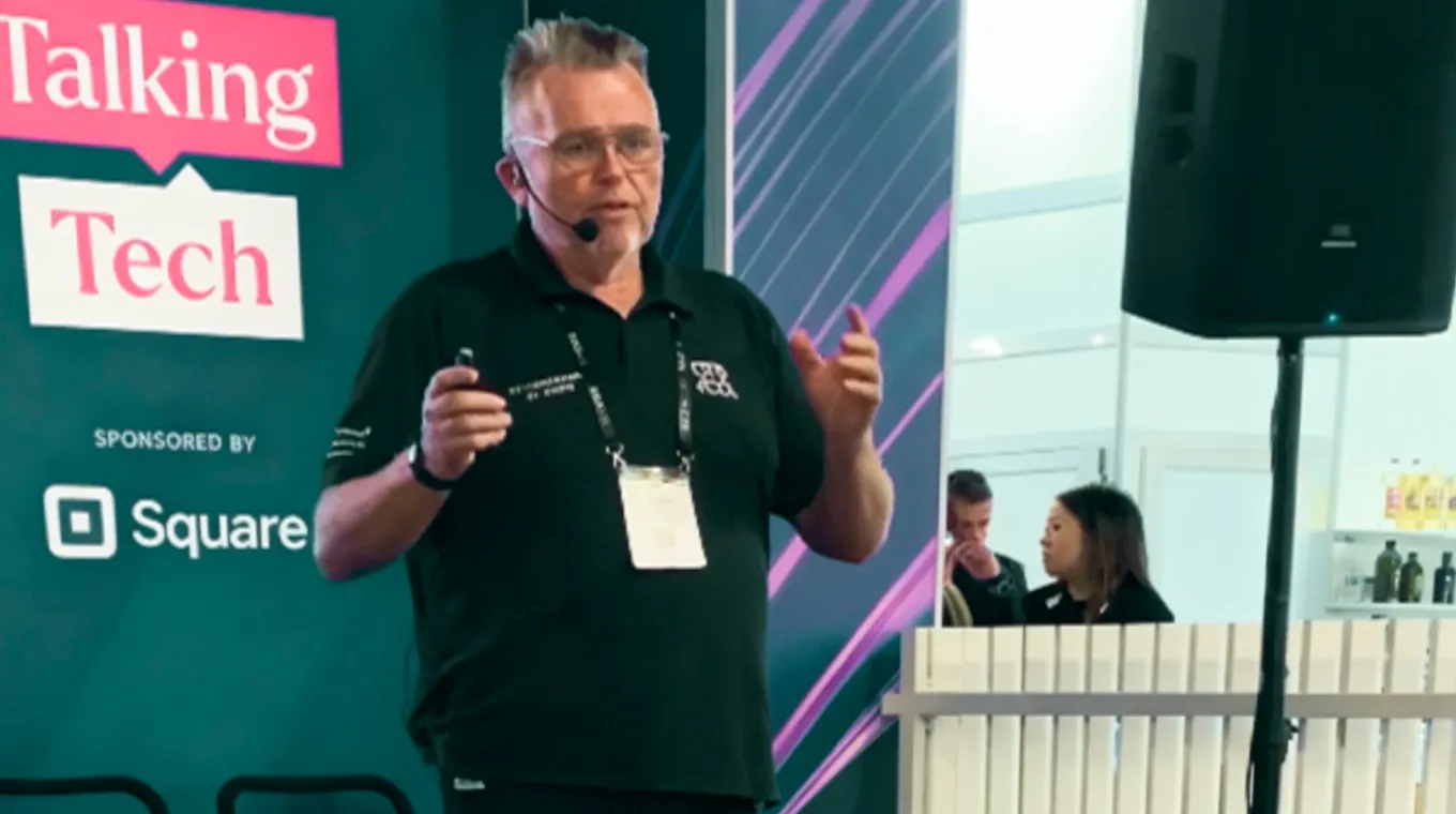 Man with headset microphone speaking on stage at a tech event sponsored by Square.