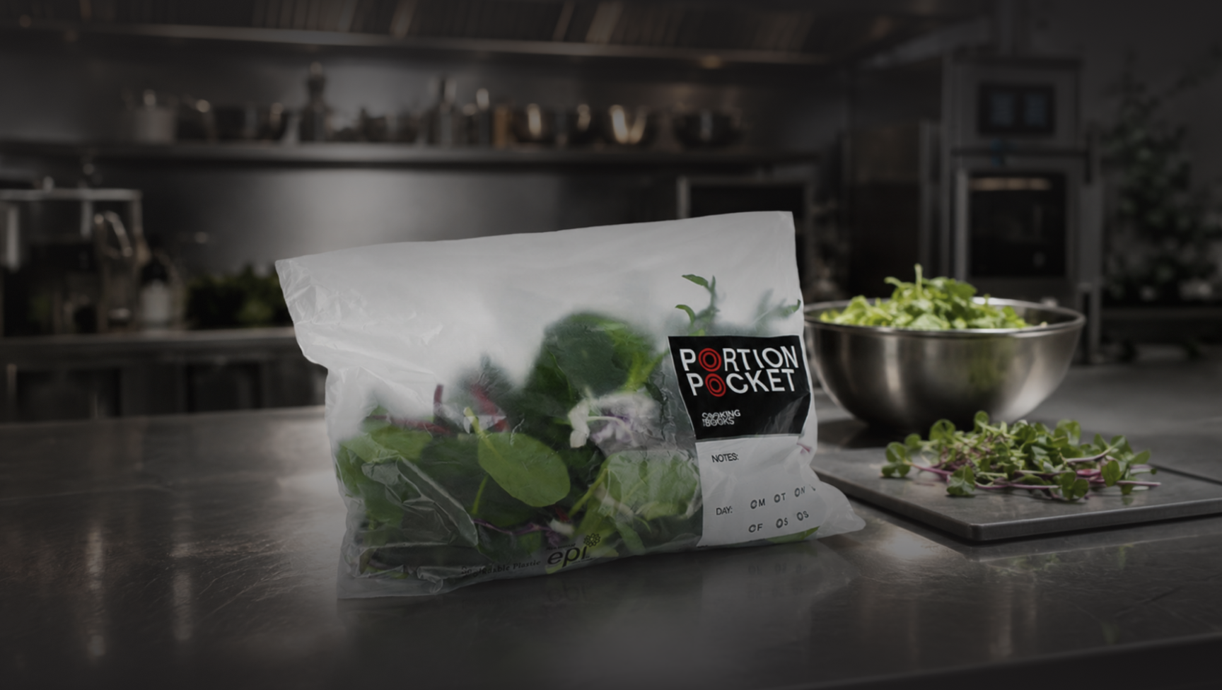 Plastic bag labeled Portion Pocket with fresh leafy greens on a stainless steel kitchen counter.