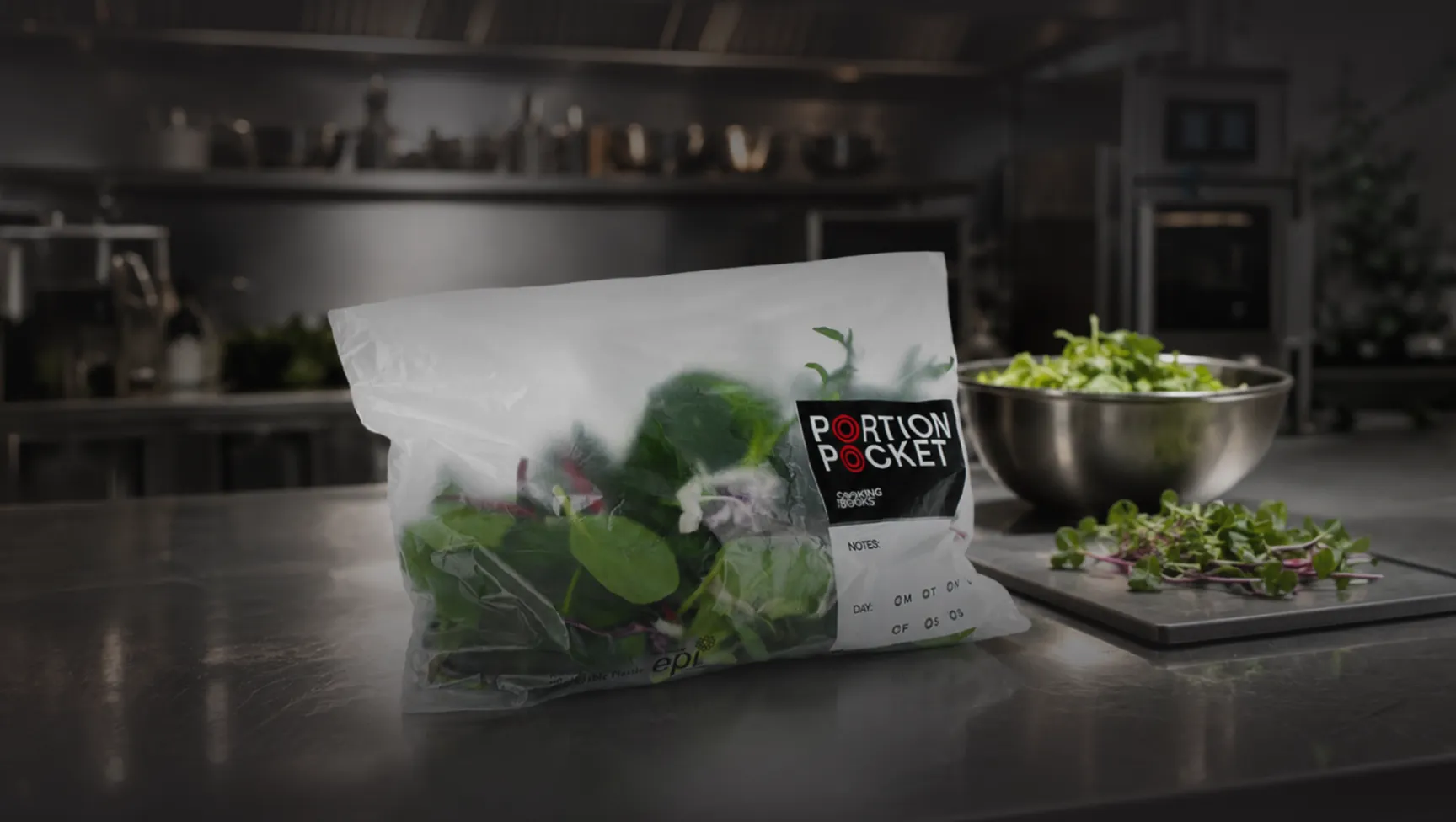 Plastic bag labeled Portion Pocket with fresh leafy greens on a stainless steel kitchen counter.