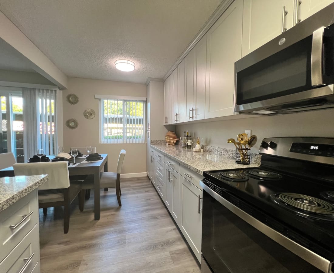 Kitchen with white cabinets and stainless steel appliances with view of dining room with table and chairs