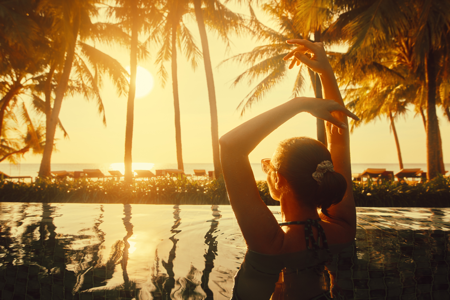 Woman in pool under palm trees stock image