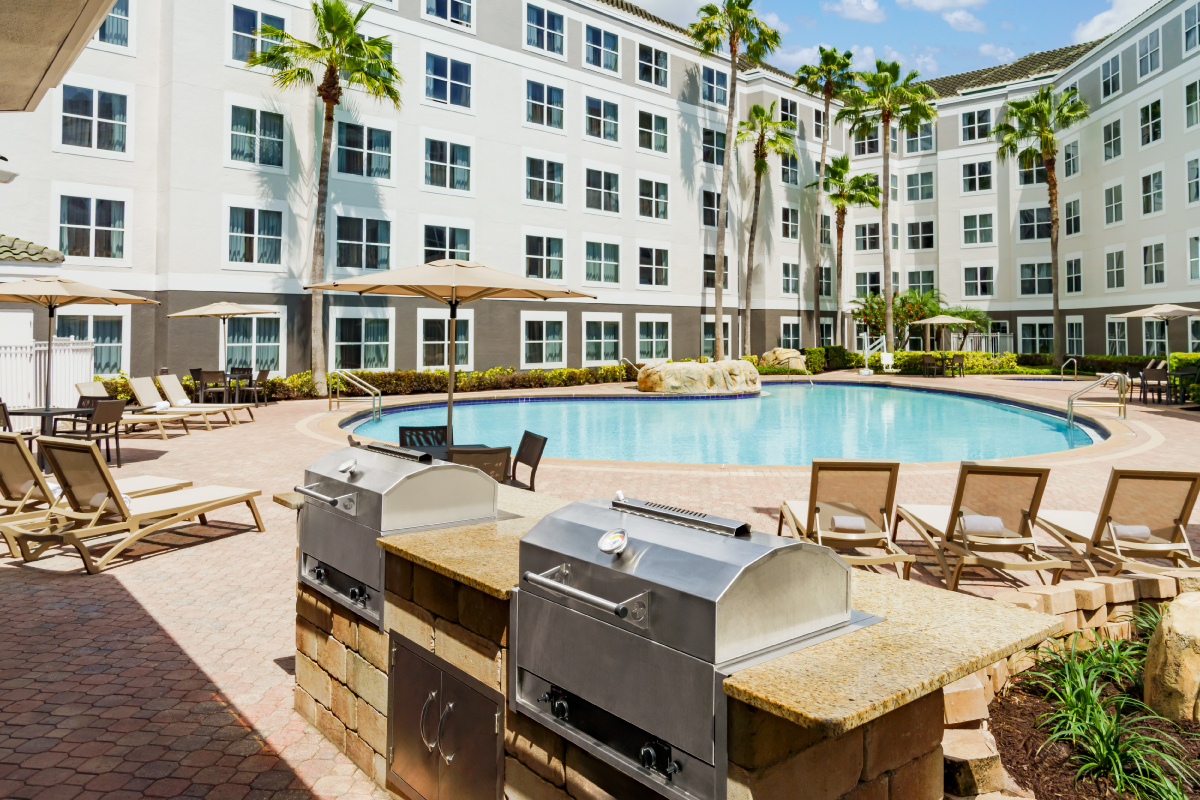 outdoor grilling area next to pool in hotel courtyard