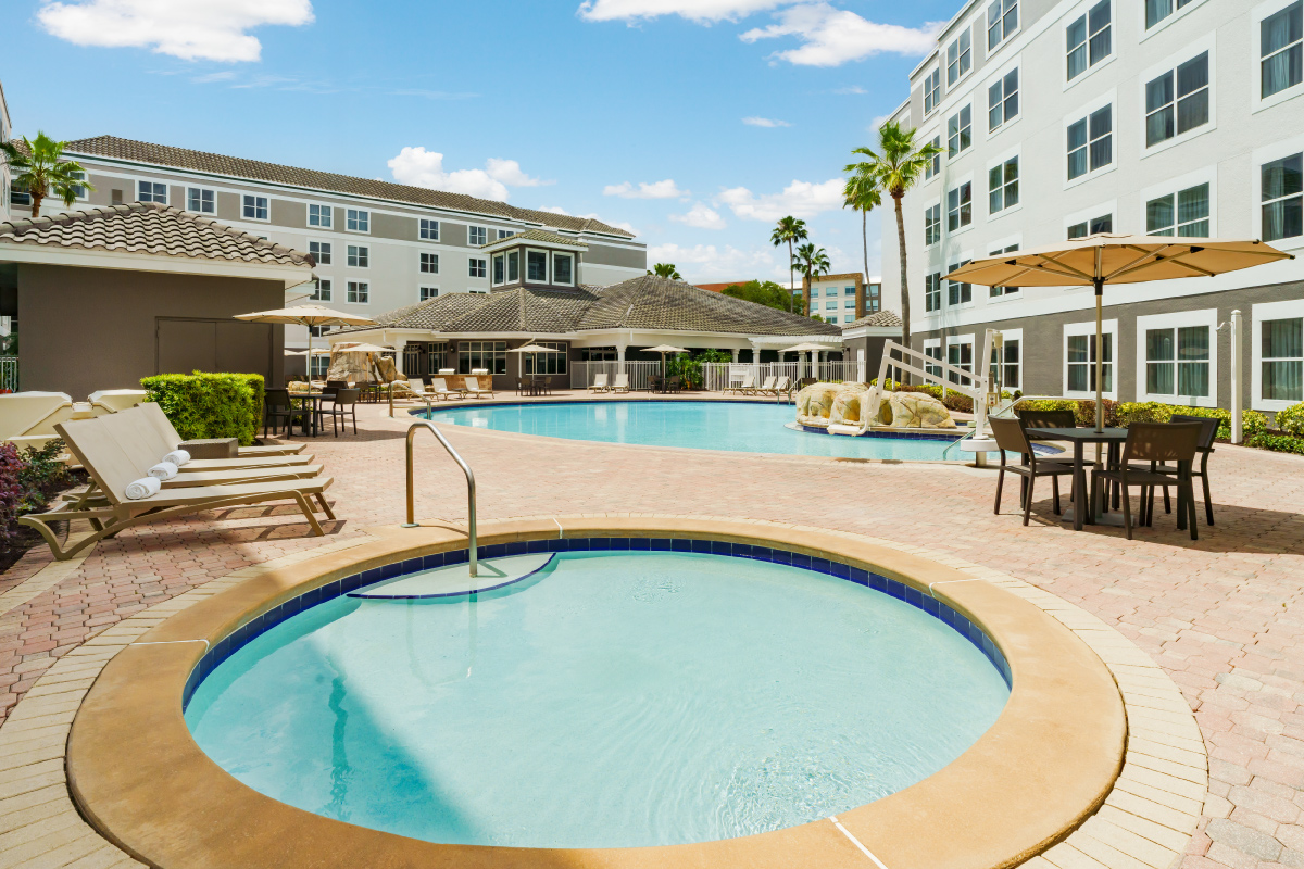 hot tub with sun chairs and main pool behind it