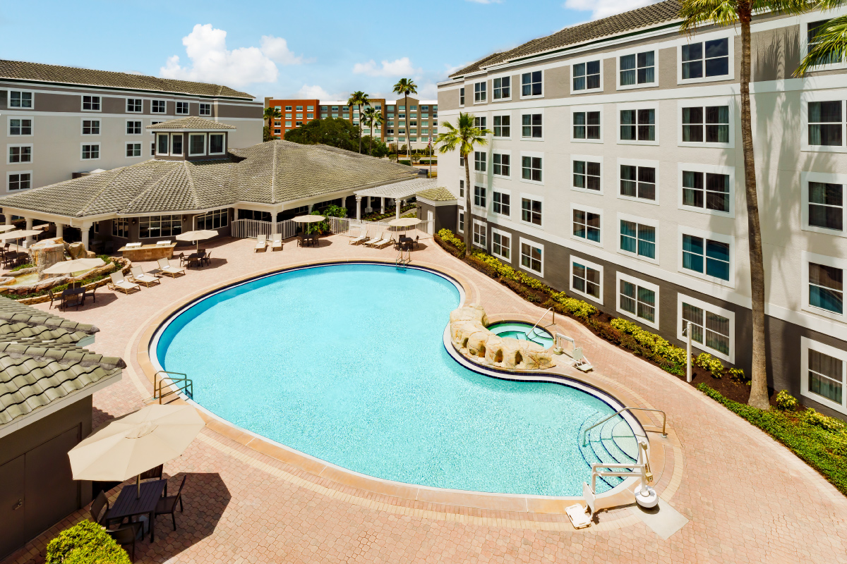 large pool in hotel courtyard with seating and hot tub