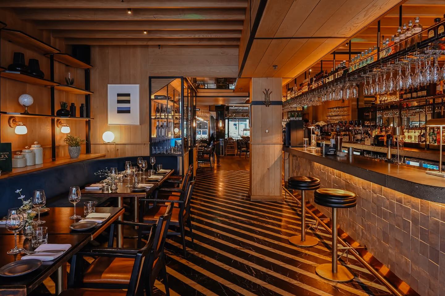 Upscale restaurant interior with red leather booths, glass pendant lights, and greenery on walls.