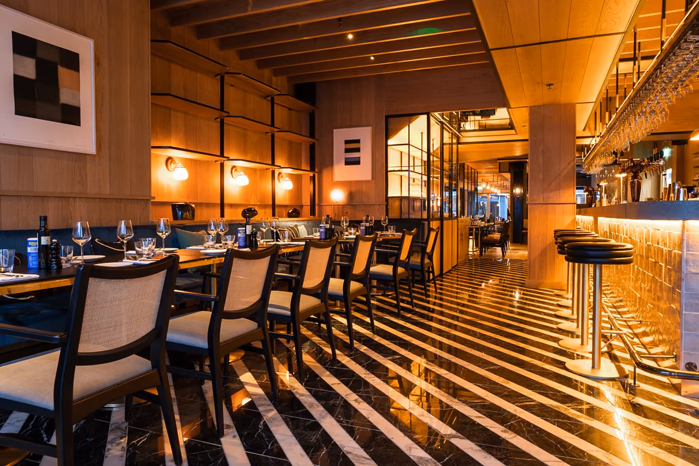 Upscale restaurant interior with red leather booths, glass pendant lights, and greenery on walls.