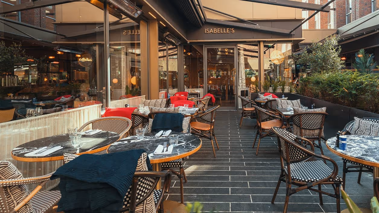 Isabelle's covered terrace on South Anne Street, set for a group dinner with rattan chairs and planting.