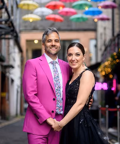 A newly married couple under a canopy of coloured umbrellas on their wedding day.