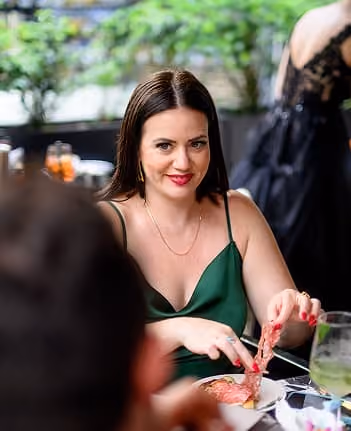 A guest in a deep green dress at the table during a wedding celebration.