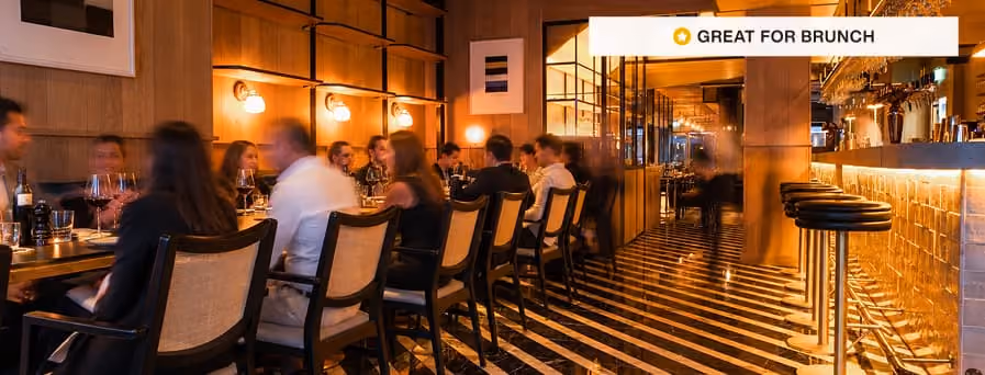 Stylish restaurant interior with red booths, round tables, hanging lights, and modern art on walls.