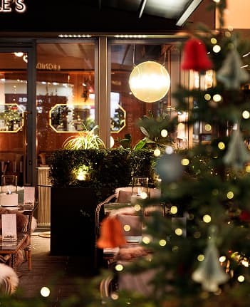 Indoor cafe seating area with warm lighting and blurred Christmas tree in foreground.