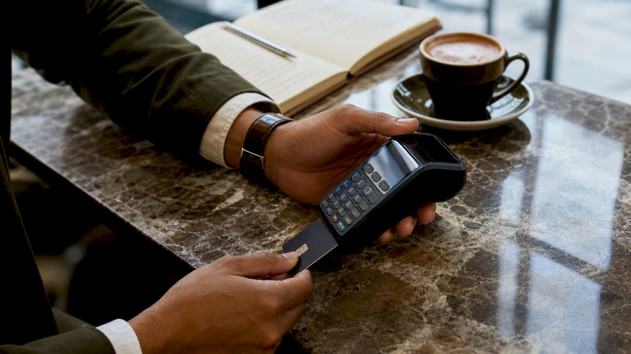 Hands inserting card into payment terminal