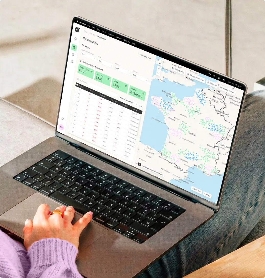Ordinateur portable sur les genoux avec carte de France et tableau de données d'analyse secteur affichés.