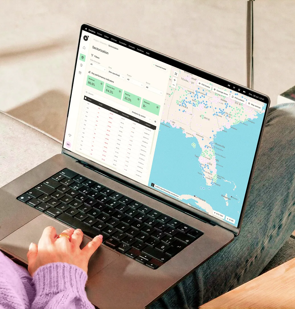 Person utilisant un ordinateur portable avec une carte interactive et des indicateurs de performance affichés à l'écran.