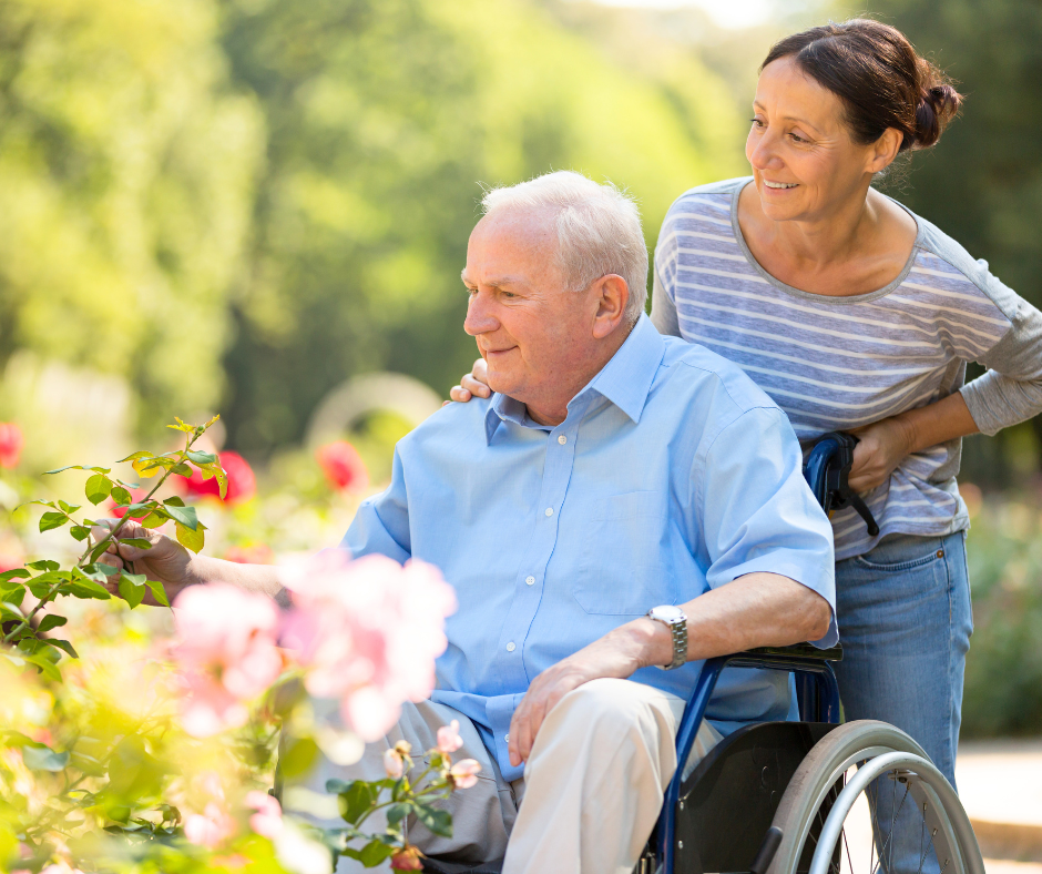 A caregiver walking with a resident through a sunlit garden
